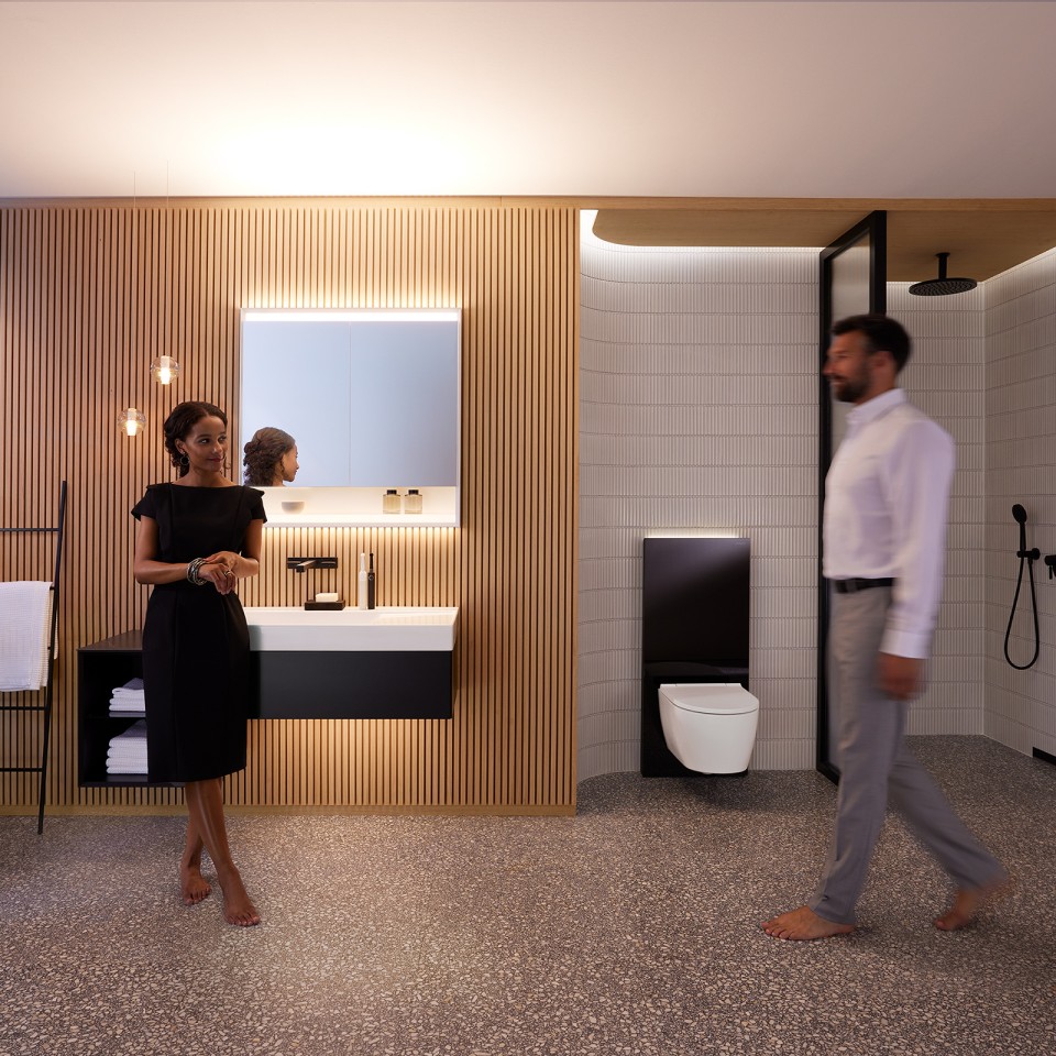 Чоловік і жінка в ідеально освітленій ванній кімнаті з меблями для ванної Geberit ONE і керамічним приладдям