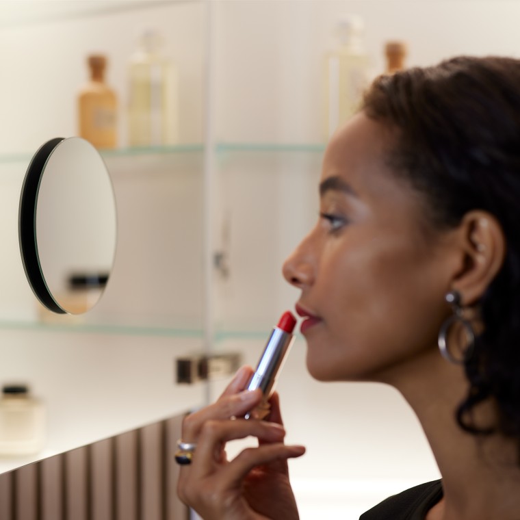 Жінка наносить макіяж перед дзеркалом Жінка наносить макіяж перед дзеркалом