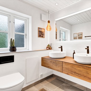 Світла відремонтована ванна кімната з двома круглими умивальниками, великим дзеркалом і дерев'яними меблями (© @triner2 і @strandparken3)