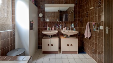Ванна кімната з коричневою плиткою і двома умивальниками