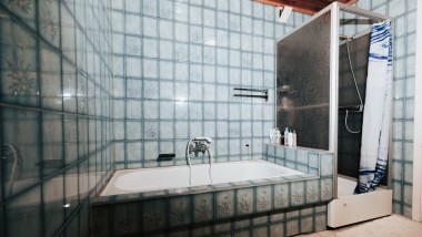 Ванна кімната з синьою плиткою, душовою кабіною та ванною